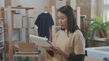 Gönüllü grubun genç Asyalı kadın üyesinin takım arkadaşlarıyla birlikte kutulara bağışları ayırırken orta ölçekli bir videosu.