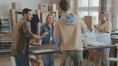 Yavaş çekimde, bağışlanmış giysilerle plastik konteynır getiren bir adam gönüllü organizasyon üyeleri olarak onu masaya yatırıyor ve kalitesini kontrol etmeye başlıyor.