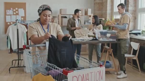 그녀의 동료들 뒷자리에서 기부금을 분류하는 느림보 사진을 아프리카 미국인 봉사자가 — 비디오