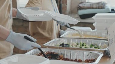 Gönüllü ekibinin plastik konteynırlara yemek koyup evsiz ve muhtaçlara verdiği orta bölüm fotoğrafları.