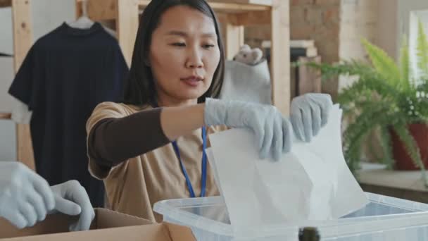 年轻的亚洲妇女和其他志愿组织成员在将垃圾在室内回收利用的过程中撕碎纸张的慢镜头 — 图库视频影像