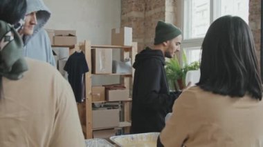 Kadın gönüllülerin, evsizlere ya da muhtaçlara plastik konteynırlarda yemek dağıtırken yavaş çekilen dikiz görüntüsü.