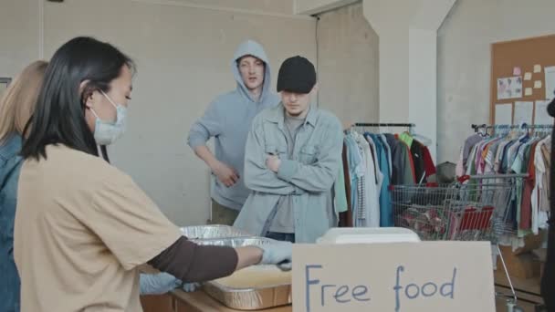 プラスチック容器の中の食料を困っている人に与えるボランティアの労働者のスローショット — ストック動画