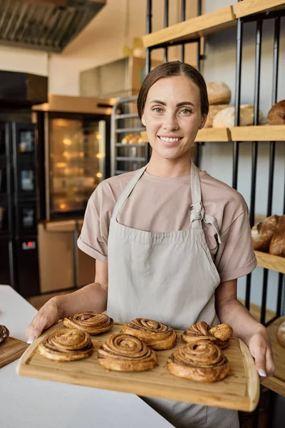 Glad kvinnlig bagare står vid arbetsplatsen — Stockfoto