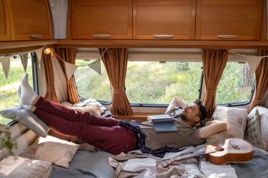 Göğsü açık, yatakta hayal kuran rahat genç bir adam.