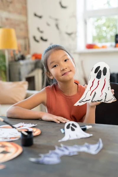 Lächelndes asiatisches Schulmädchen mit Papiergeist für Halloween vorbereitet — Stockfoto