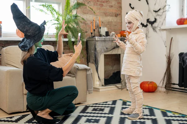 Female in witch costume taking photo of her little son — Stock Photo, Image