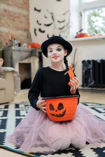 Gelukkig meisje in halloween kleding holding mand met traktaties — Stockfoto