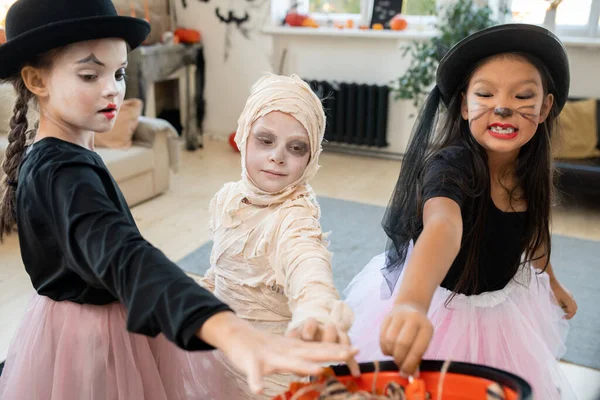 Três crianças em trajes de Halloween inteligentes tomando guloseimas — Fotografia de Stock