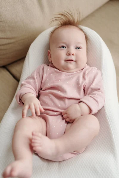 Adorable bebé en ropa rosa relajante en una pequeña cama suave blanca —  Fotos de Stock