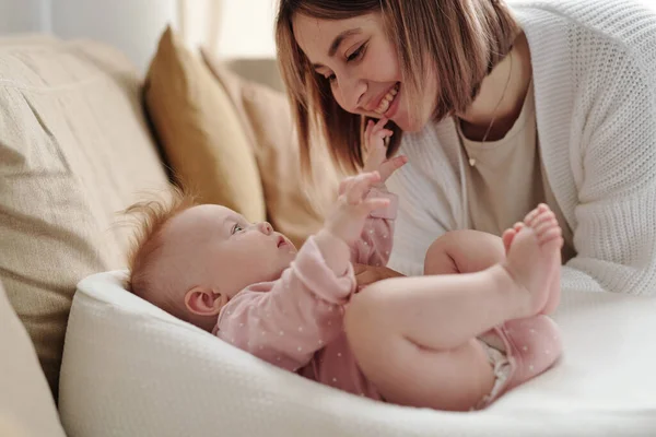 Jovem sorrindo mulher se curvando sobre sua filha bebê bonito — Fotografia de Stock