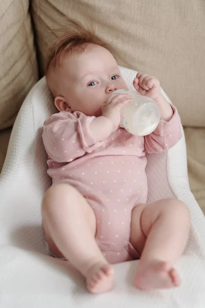 Adorable baby girl looking at you while eating milk — Stock Photo, Image