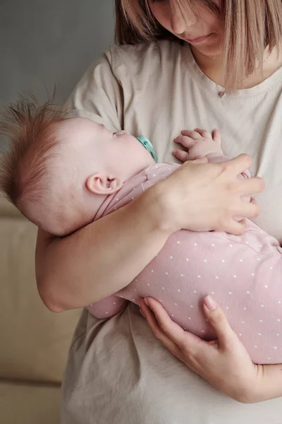 Söt baby i rosa kläder sover på händerna på sin mor — Stockfoto