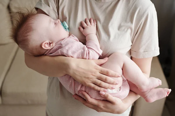 Söt liten flicka med napphållare sover på händerna på sin mamma — Stockfoto