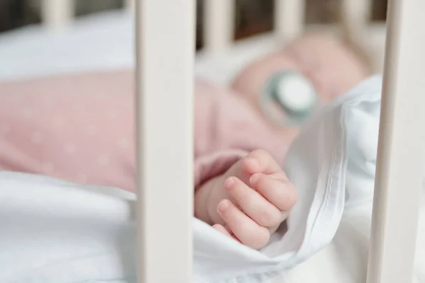 Små fingrar och hand lilla flicka sover i spjälsäng — Stockfoto
