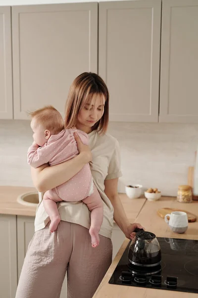 Jonge moeder met schattige baby dochter stand by elektrisch fornuis — Stockfoto