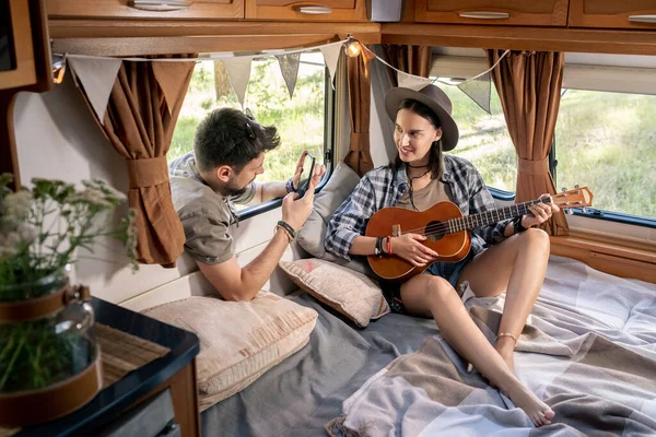 Молодий чоловік фотографує свою дівчину з гітарою — стокове фото