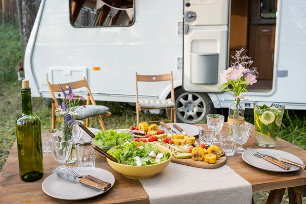 Table servie avec de la nourriture maison et des boissons contre la maison sur roues — Photo