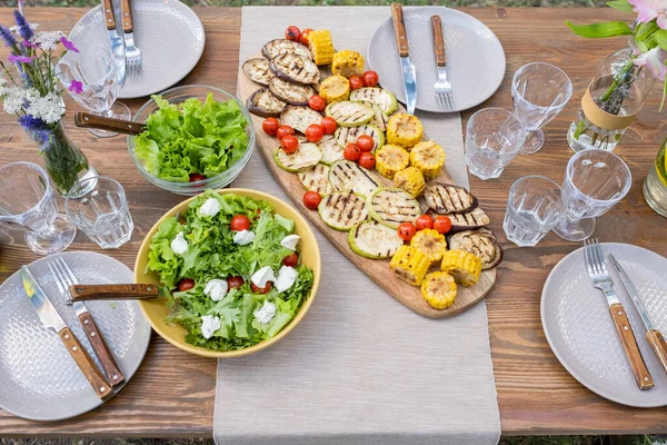 Mesa servida con comida vegetariana, vasos y platos —  Fotos de Stock