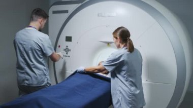 Modern klinikte çalışan iki radyologla ilgilenmeden önce 9 yaşındaki bir kızın tarama masasına uzanması.