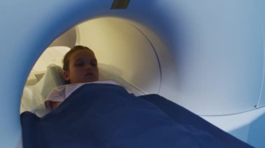Modern klinikte tıbbi muayeneden sonra küçük kızın MRI tüpünden çıkarken yavaş çekim.