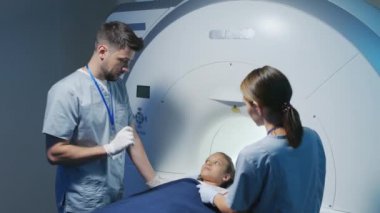 Radyoloji uzmanıyla asistanının 9 yaşındaki bir kıza MRI incelemesini anlatırken çekilmiş yavaş bir fotoğrafı.