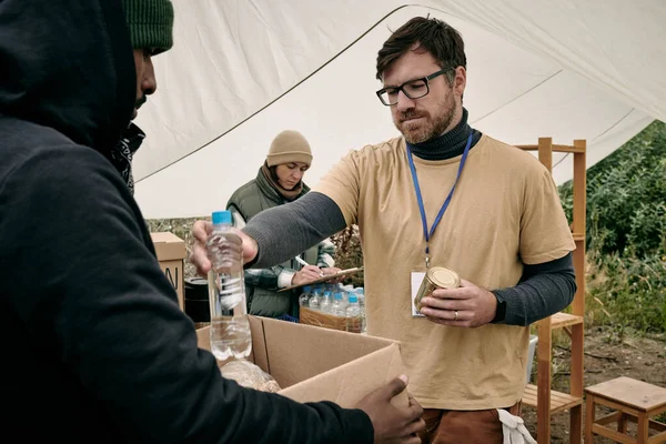 Vrijwilliger die water geeft aan daklozen — Stockfoto