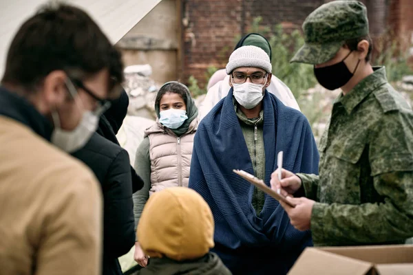 Мигранты в масках, стоящие в очереди за едой и лекарствами — стоковое фото