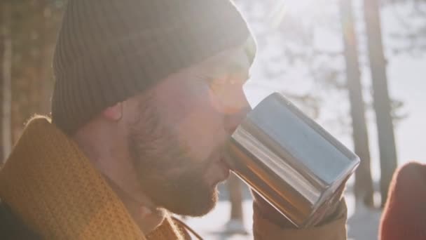 在冬季的森林徒步旅行中 紧紧抓住一个留着胡子的年轻人 他正在用不锈钢杯子喝热茶 — 图库视频影像