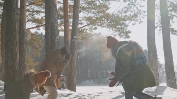 幸せな男のスローショット 女性と女の子で暖かい冬服投げ雪玉で森の中で晴れた日 — ストック動画