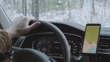 Kışın telefonunda dijital harita uygulaması kullanarak tanınmayan bir adamın araba kullanması.