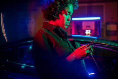 Akıllı telefonlu bir kız elektrikli araba için para ödüyor.