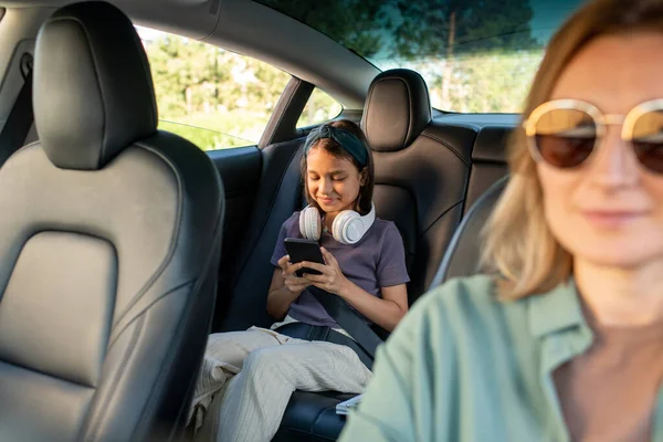 Happy schoolmeisje met hoofdtelefoon scrollen in smartphone — Stockfoto