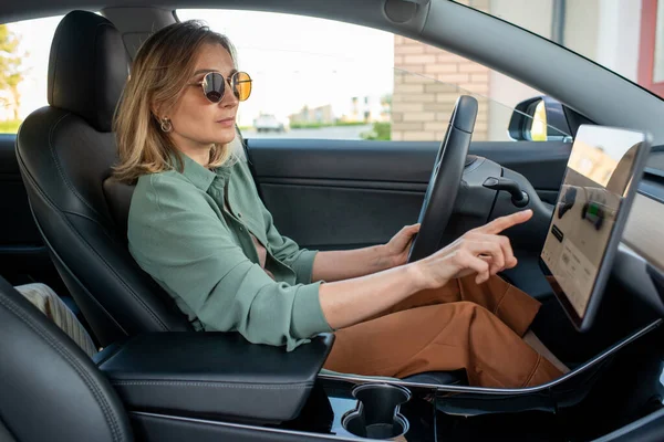 Jonge vrouwelijke bestuurder wijst naar display tijdens het kiezen van bestemming plaats — Stockfoto