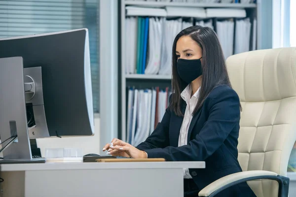 Secretária séria jovem olhando para a tela do computador durante a rede — Fotografia de Stock