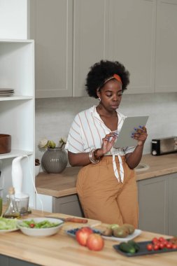 Genç, ciddi bir kadın tablette video tariflerini tarıyor.