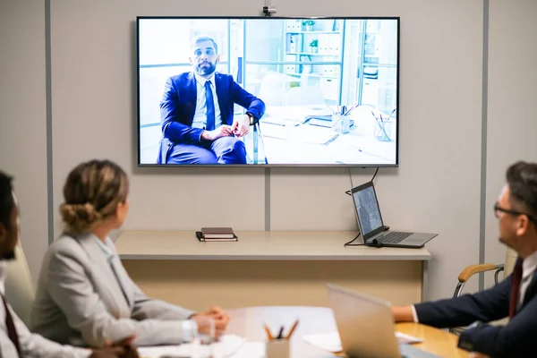 Intercultural audience looking at mature businessman on display — Stock Photo, Image