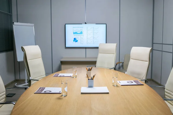 Sillones alrededor de mesa grande con papeles, vasos y bolígrafos — Foto de Stock