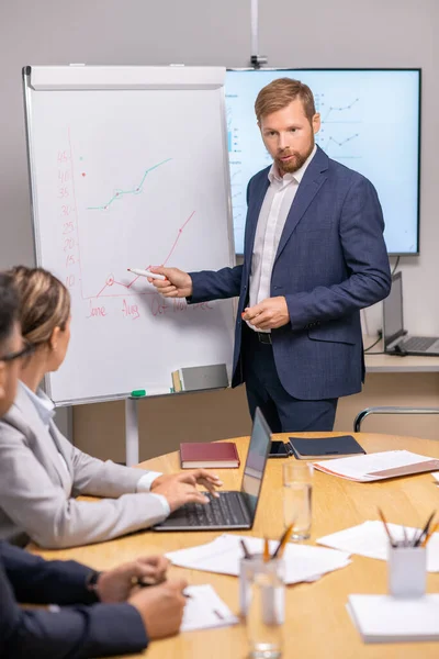 Jonge serieuze zakenman wijst naar grafiek op whiteboard — Stockfoto