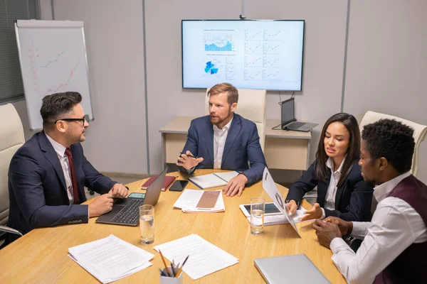 Twee zakenlieden raadplegen over spraakpunten, terwijl twee interculturele collega 's discussiëren over papers — Stockfoto