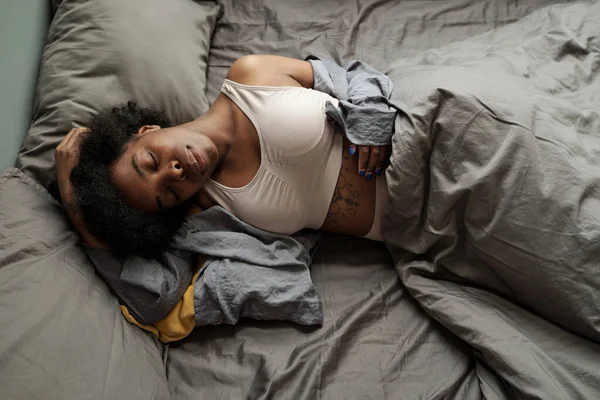 Junge müde Frau schläft unter grauer Decke — Stockfoto