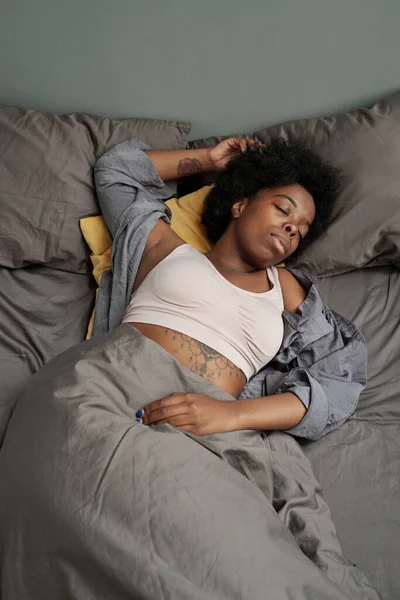 Jonge Afrikaanse vrouw slapen in bed met grijze kussens — Stockfoto