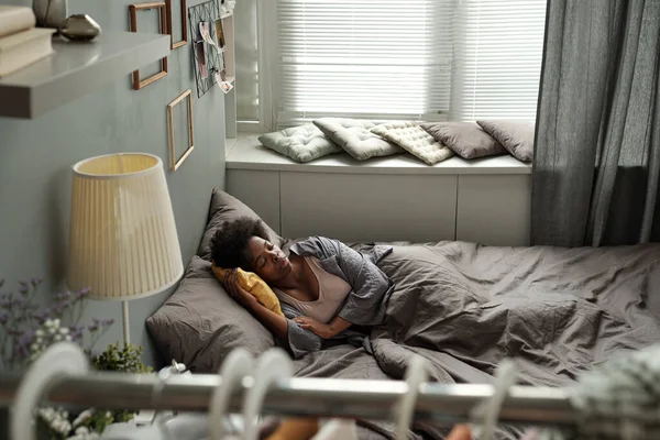 Contemporanea giovane donna sdraiata a letto in ambiente domestico — Foto Stock