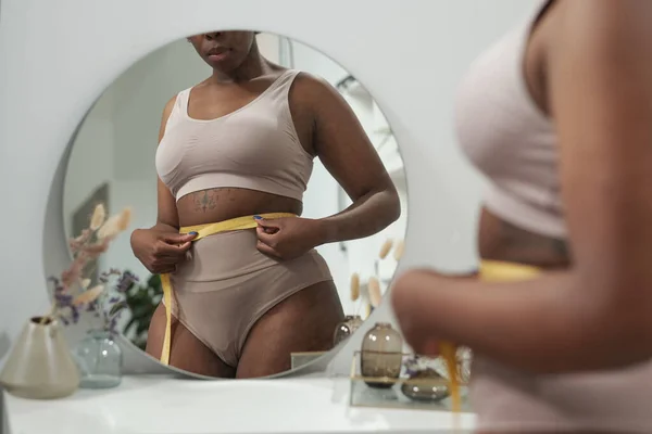 Young female in underwear measuring her waist after everyday training — Stock Photo, Image