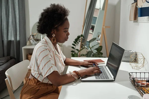 Ung seriös hemmakontor chef sitter vid skrivbordet framför laptop — Stockfoto