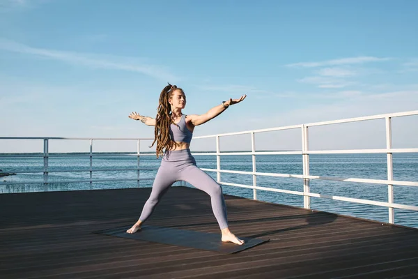 Giovane donna scalza in piedi sul tappeto durante la pratica dello yoga — Foto Stock