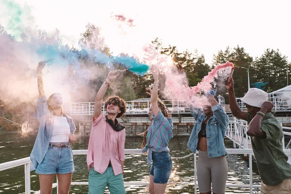 Веселые молодые люди в повседневной одежде танцуют с фейерверками — стоковое фото