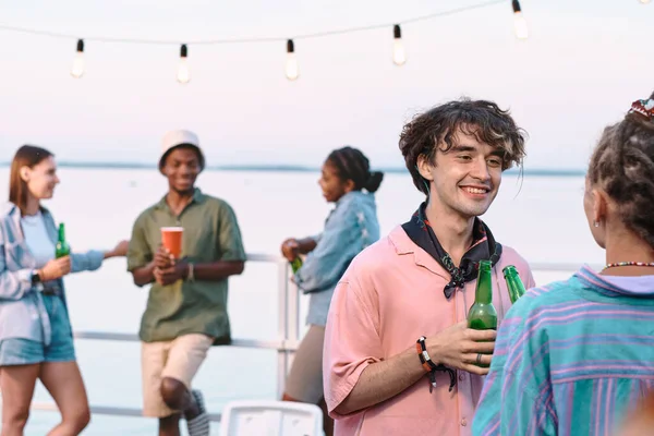 Feliz joven pareja amorosa con botellas de cerveza interactuando en la fiesta al aire libre —  Fotos de Stock