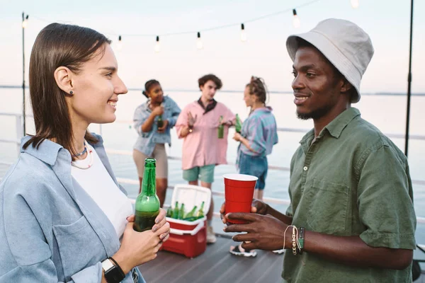Joven pareja contemporánea con bebidas mirándose con sonrisas —  Fotos de Stock
