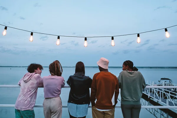 Rij van jonge rustgevende vrienden staan op pier — Stockfoto